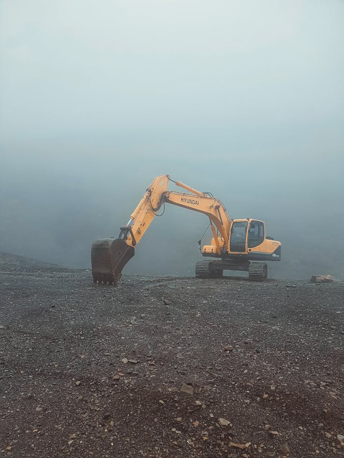 menu-03 A solitary excavator on a misty day in Krasnaya Polyana, Russia, set against a barren landscape.