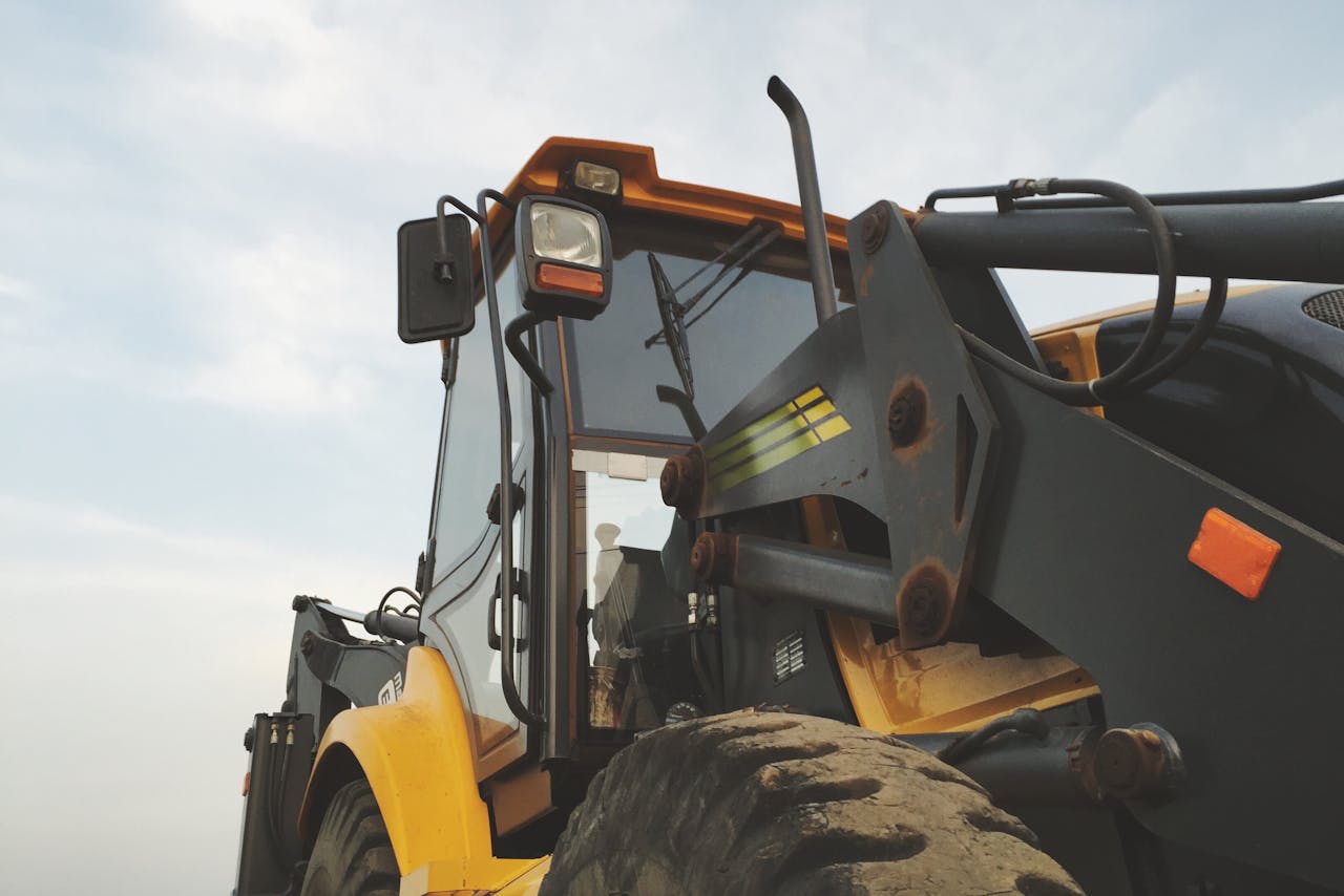 menu-01 Detailed view of a yellow excavator against a clear sky at a construction site.